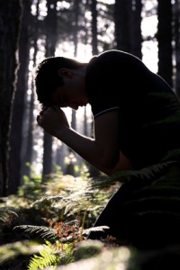 Man kneeling praying in the forest