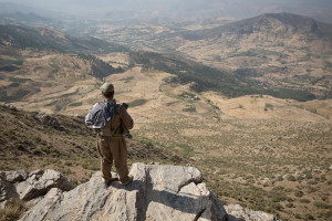 24/08/2015. Khandil Mountains, Iraq. Ryan, a former US soldier now working with the Iranian Kurdish KDP-I, watches from a hilltop close to one of the groups bases in the Khandil Mountain Range on the Iraqi side of the Iran-Iraq border. After many years of training and staying away fro the border with Iran the Kurdish Democratic Party Iran (KDP-I) are now returning to their bases along the mountainous areas next to the Iraqi border with Iran. The group, consisting of Iranian Kurds who are disaffected with the Iranian regime and its human rights abuses, is now preparing to work against the Iranian State, though has not yet started to fight.